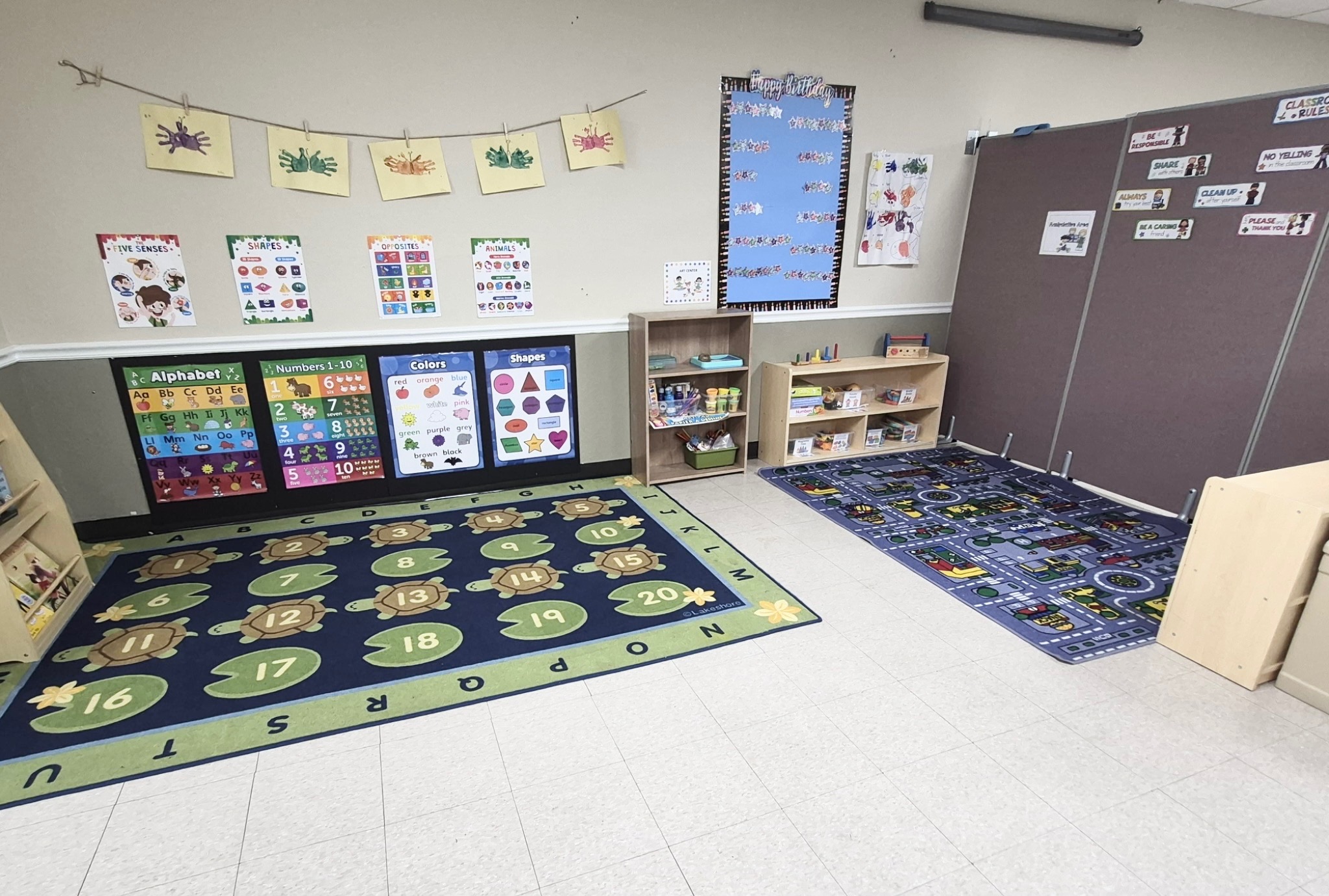 Classroom with alphabet and number learning rugs, art displays and reading shelves